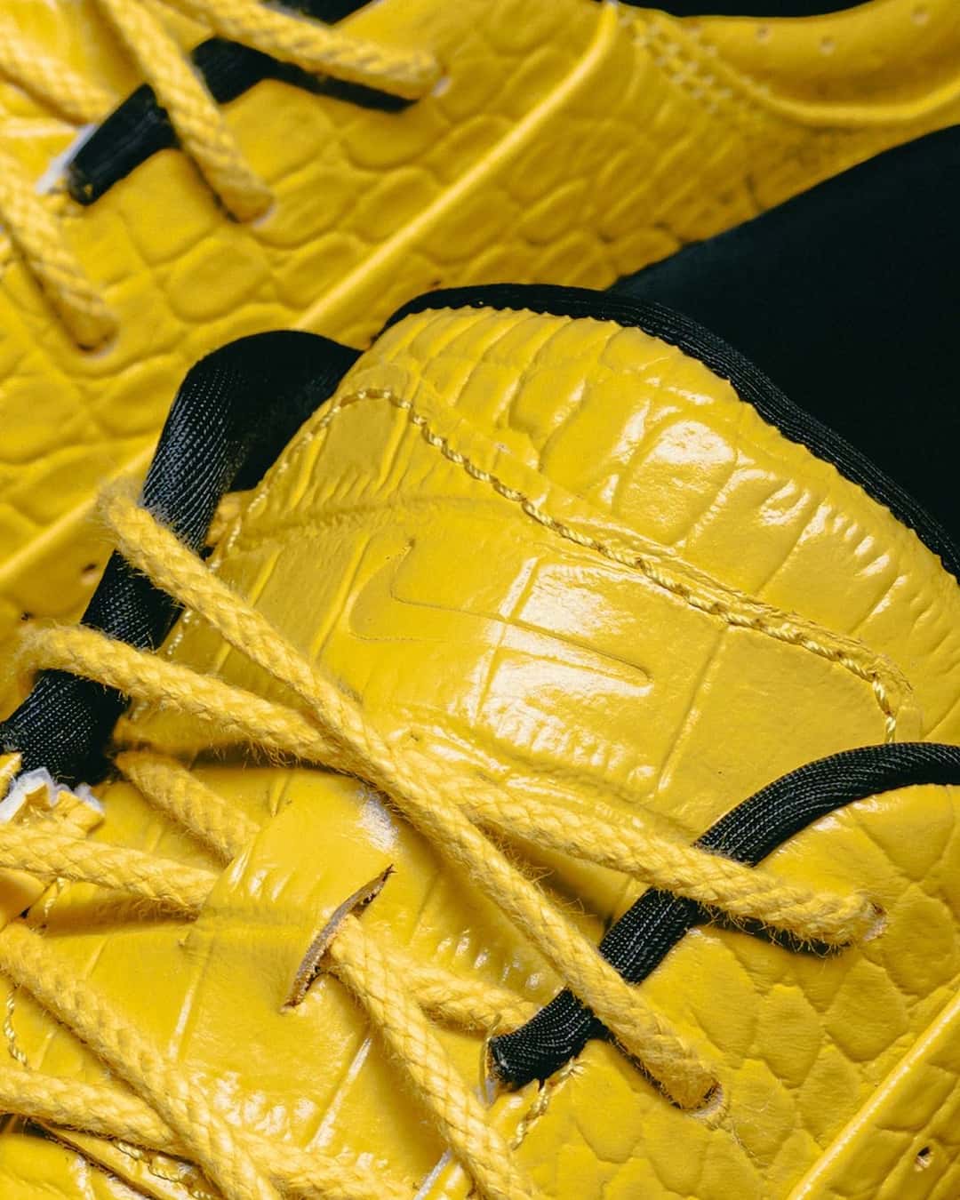 Primer plano del empeine del Nike Air Max Goadome Low Yellow Croc, con cuero amarillo brillante grabado tipo cocodrilo, cordones amarillos de cuerda, pasacordones negros y un swoosh grabado en relieve sobre la lengüeta