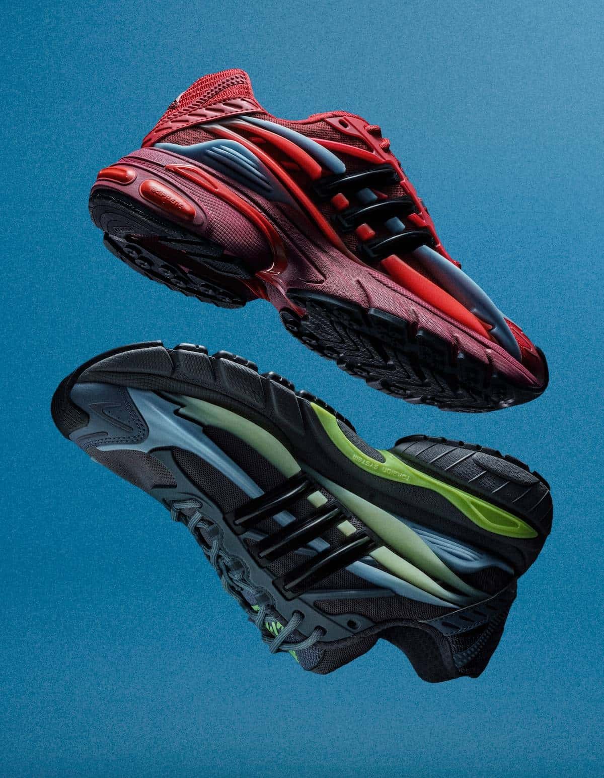 Pharrell x adidas Adistar Jellyfish Red y Storm flotando sobre fondo azul: arriba el par rojo con Three Stripes negras y capas grises, abajo el par gris oscuro con detalles verde claro y volt
