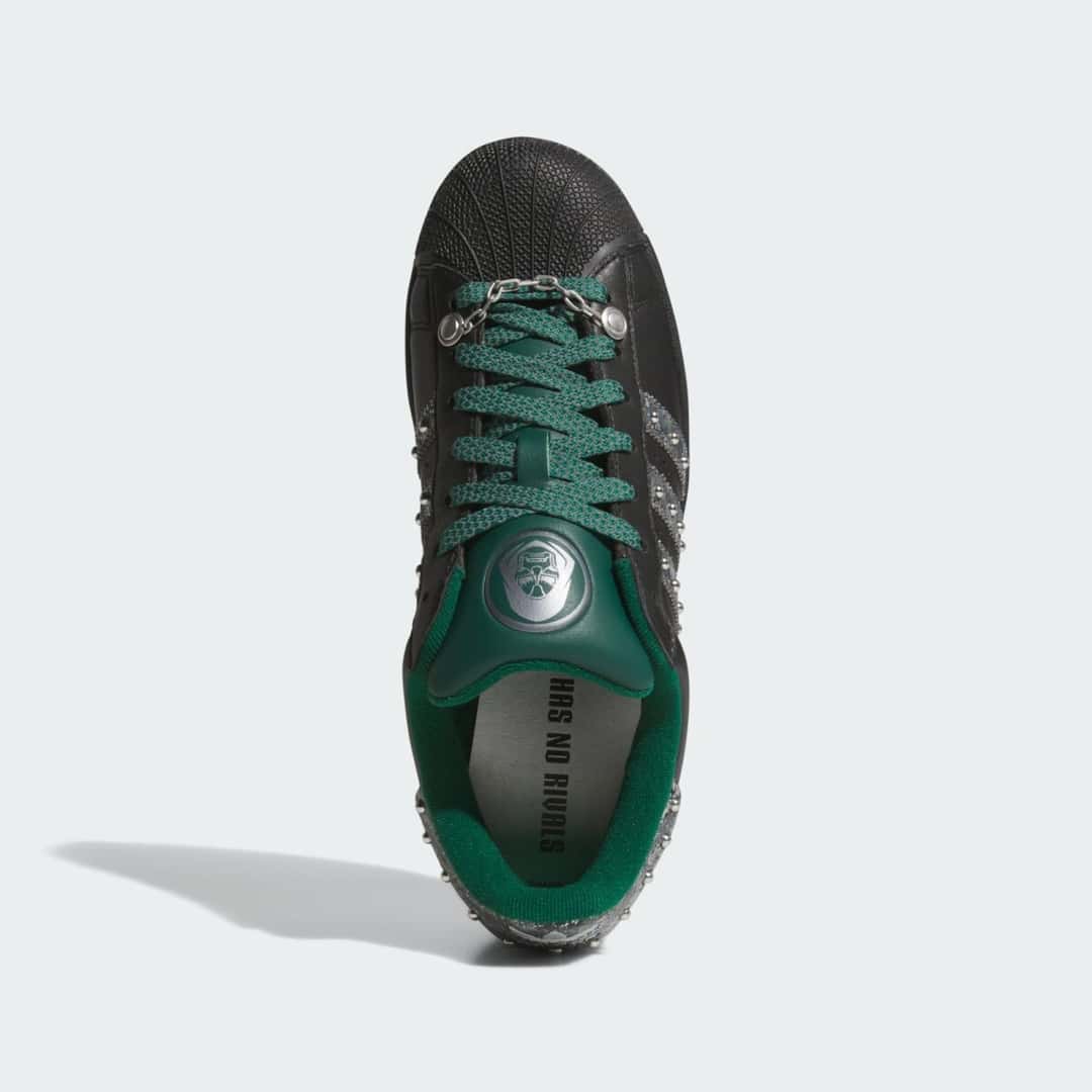 Vista desde arriba del adidas Superstar Doctor Doom con cordones verdes, la máscara plateada en la lengüeta y la frase Has No Rivals en la plantilla