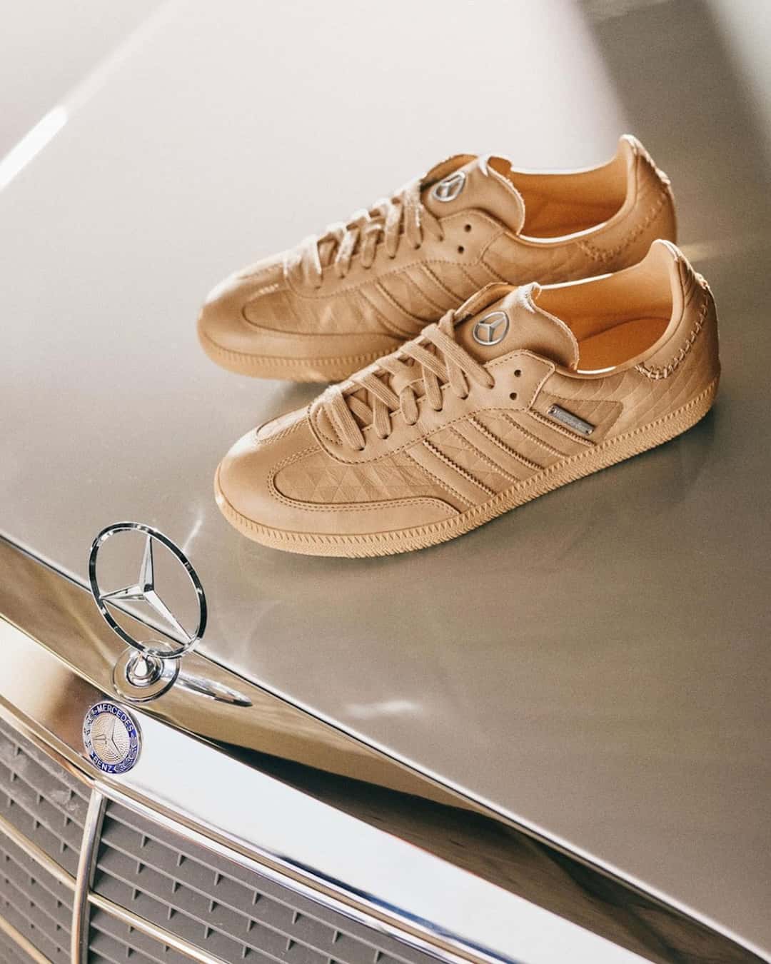 adidas Samba OG x Mercedes-Benz en Magic Beige sobre el capó de un Mercedes clásico, con la estrella en la lengüeta y la placa metálica al costado