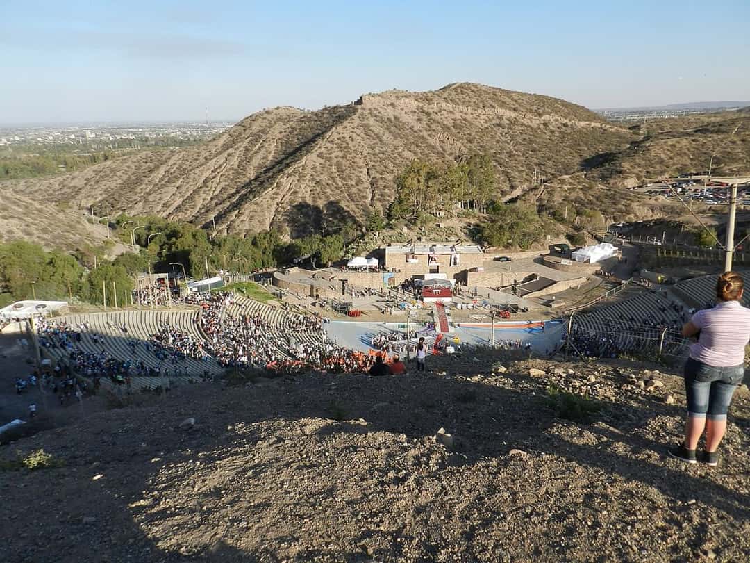 El Teatro Griego Frank Romero Day visto desde el cerro, con las gradas llenas de público frente al escenario y las montañas de fondo (foto de archivo). Foto: Federico Gomez Aghetta, dominio público, vía Wikimedia Commons
