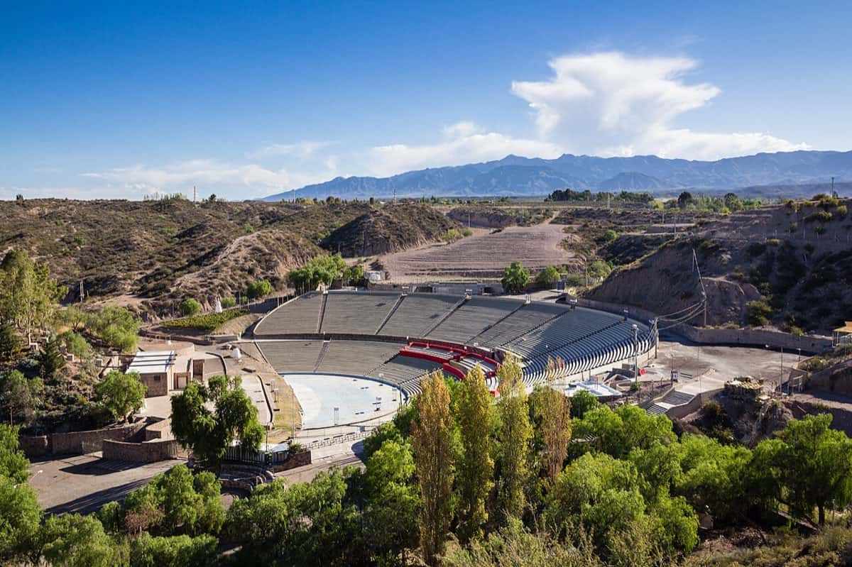 Vista aérea del Teatro Griego Frank Romero Day de Mendoza, con sus gradas grises en semicírculo rodeadas de árboles y la cordillera de fondo