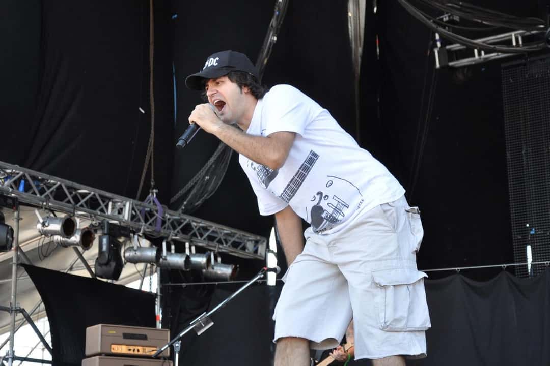 Andrés Ciro Martínez canta con gorra y remera blanca, micrófono en mano, en un show al aire libre en Tigre (foto de archivo, junio de 2013). Foto: Municipio de Tigre, CC BY 2.0, vía Wikimedia Commons