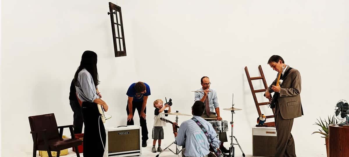 Los integrantes de DIIV tocan en un estudio blanco con amplificadores, una batería y una escalera de madera, junto a un nene con una cámara, en una imagen del video oficial de «Kid»