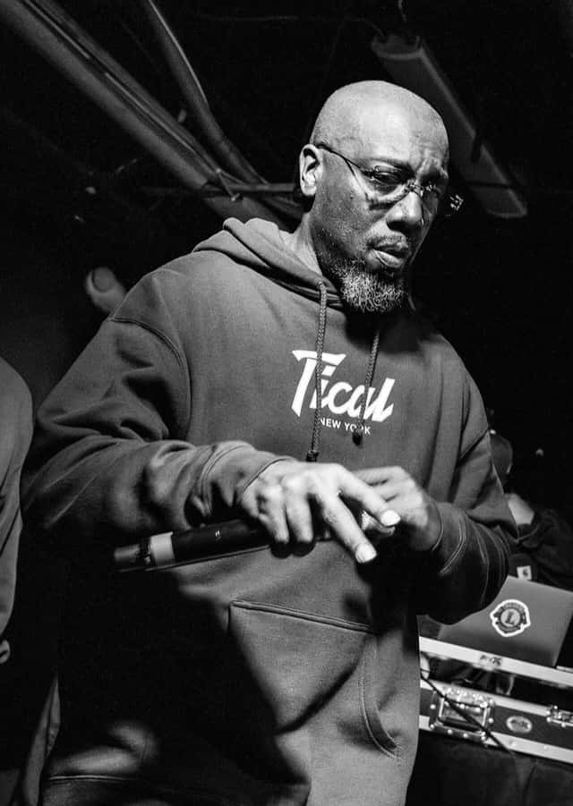 Inspectah Deck en vivo, de buzo gris y anteojos, con el micrófono en la mano frente a una consola, en Albany, en 2024. Foto: Lygonstreet, CC BY-SA 4.0, vía Wikimedia Commons (foto de archivo)