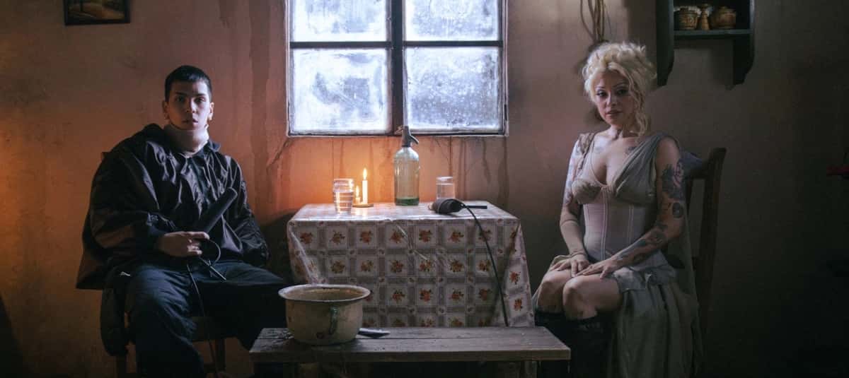 Milo J y Mon Laferte sentados en una casita a la luz de una vela, en una imagen de prensa de La Jangada