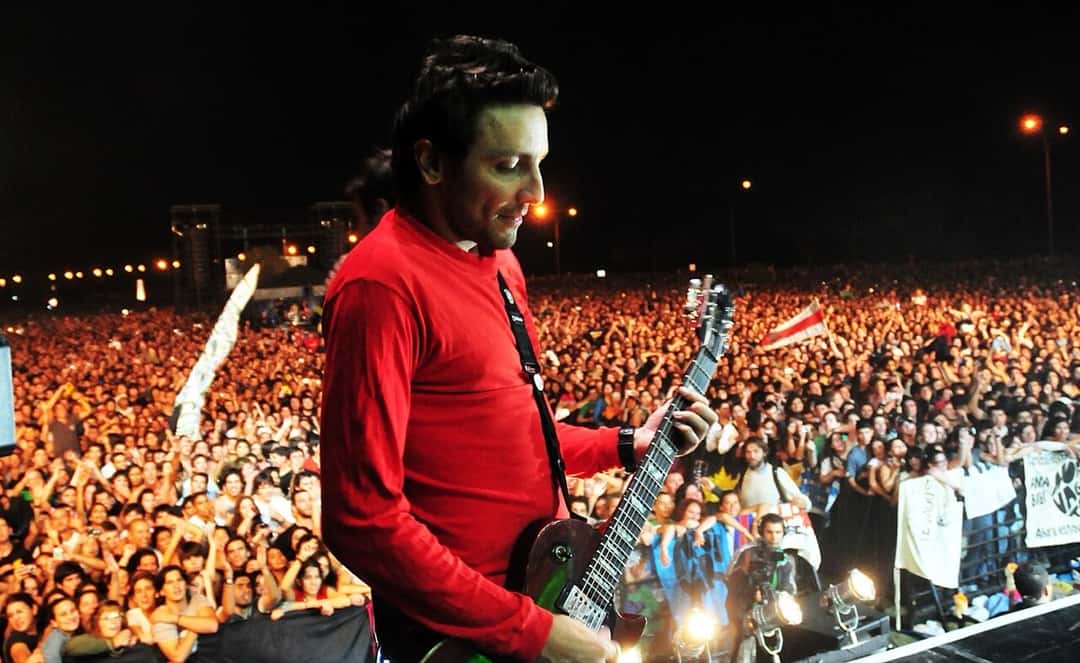 Un guitarrista de No Te Va Gustar, de buzo rojo, toca frente a una multitud en las Canteras del Parque Rodó de Montevideo, en el show gratuito de marzo de 2011 (foto de archivo). Foto: Bicentenario Uruguay, CC BY-SA 2.0, vía Wikimedia Commons