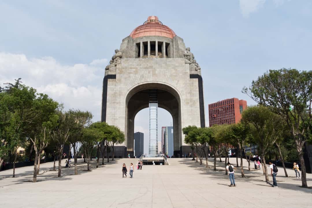 Monumento a la Revolución, en Ciudad de México, con su cúpula y sus arcos de piedra sobre una plaza abierta y arboleda a los costados. Foto: ismael villafranco, CC BY 2.0, vía Wikimedia Commons