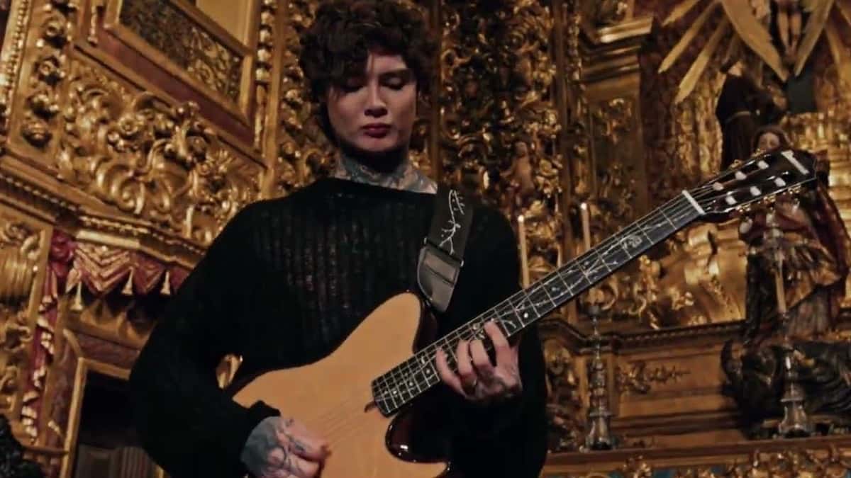 Un integrante de Polyphia toca la guitarra frente a un altar barroco dorado en el video oficial de «Power In The Blood» (fotograma del video oficial)