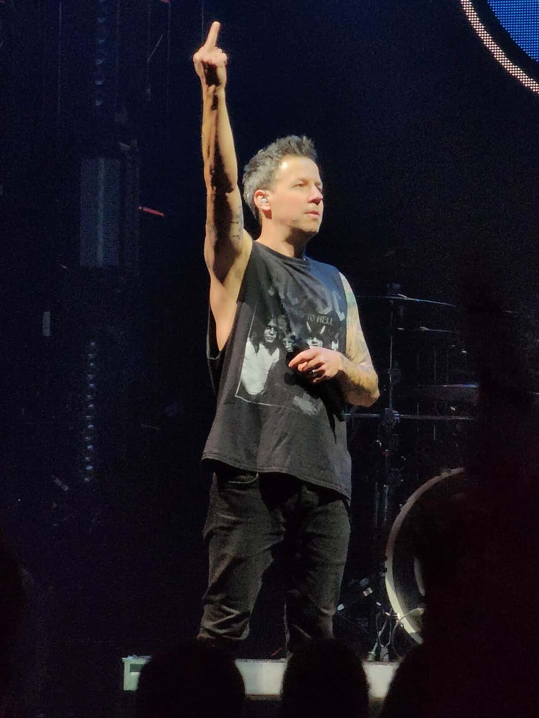 Pierre Bouvier, cantante de Simple Plan, con musculosa negra, señala hacia arriba con un brazo sobre el escenario, en noviembre de 2022 (foto de archivo). Foto: Crisco 1492, CC BY-SA 4.0, vía Wikimedia Commons