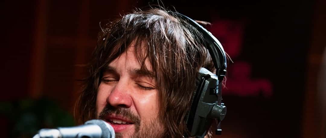 Kevin Parker, de pelo largo y auriculares, canta con los ojos cerrados frente a un micrófono en el estudio de Like A Version, en una imagen oficial de triple j