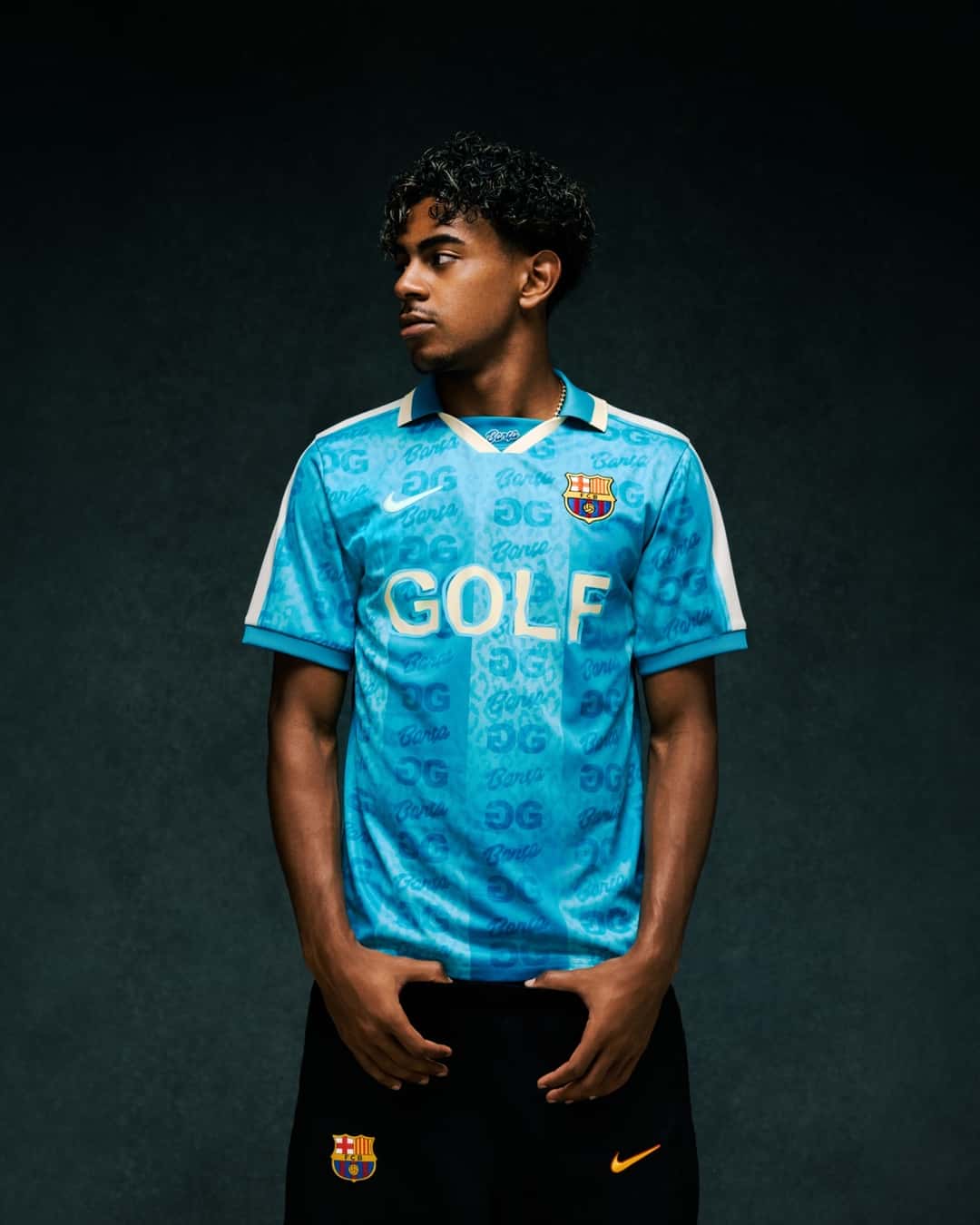 Un joven posa con la camiseta retro celeste del Barcelona con el logo de GOLF y un short negro con el escudo del club, sobre un fondo oscuro, en una foto de prensa de la colección
