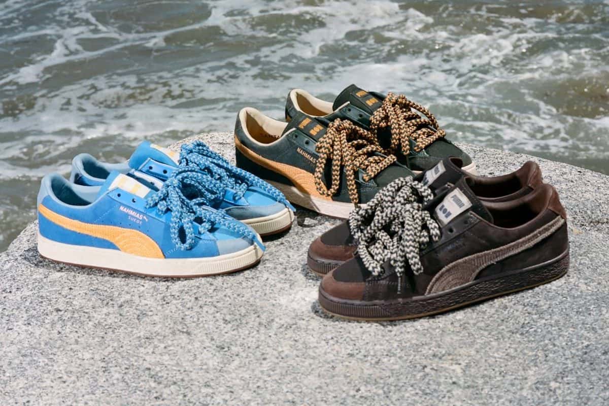 Las tres NAHMIAS x PUMA Suede Crochet sobre una roca junto al mar: la azul eléctrico, la verde y la marrón chocolate, con cordones tejidos gruesos