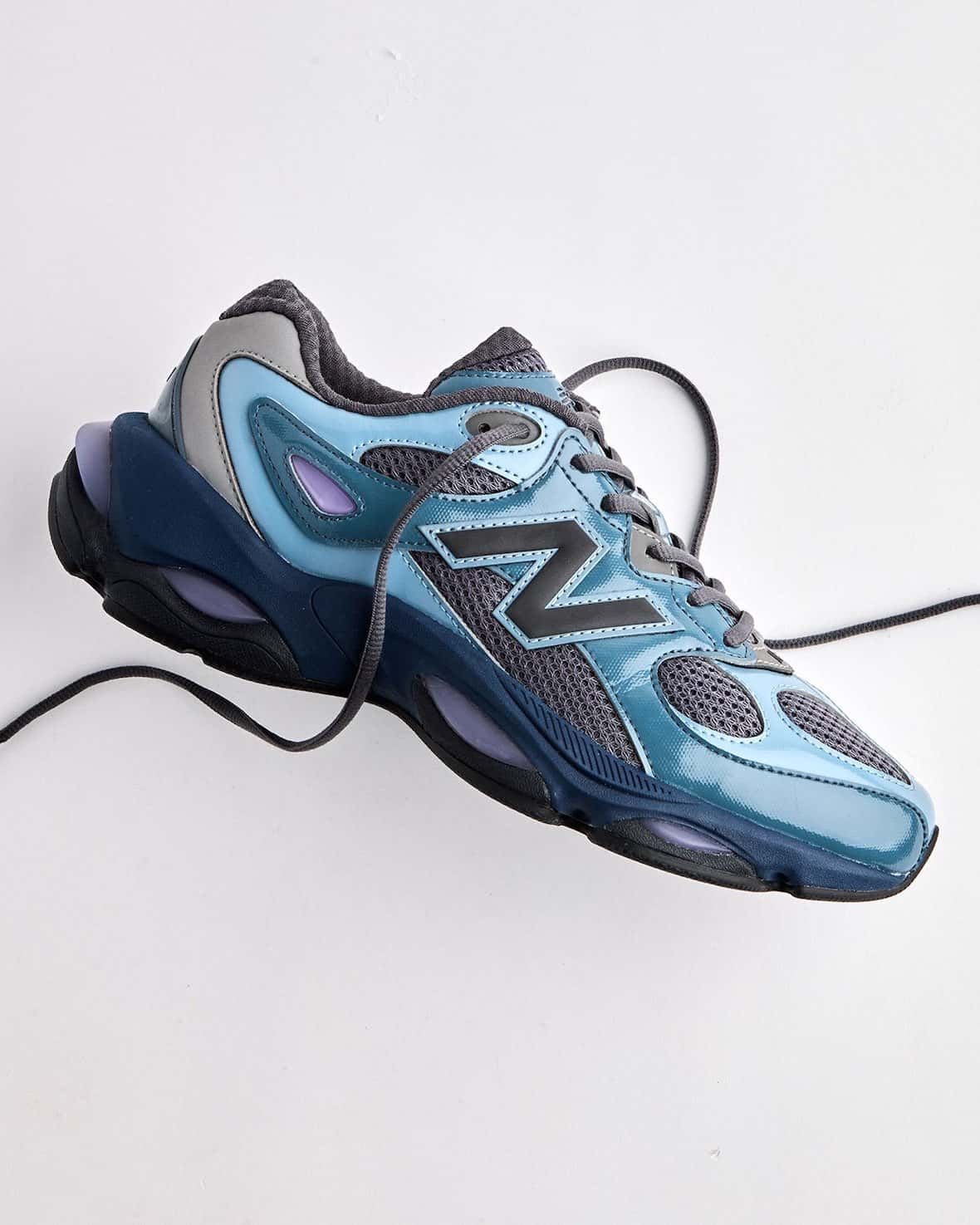 New Balance 983 Shadow Blue de perfil con overlays celestes brillantes, malla gris, logo N oscuro y pods ABZORB violetas en la mediasuela azul