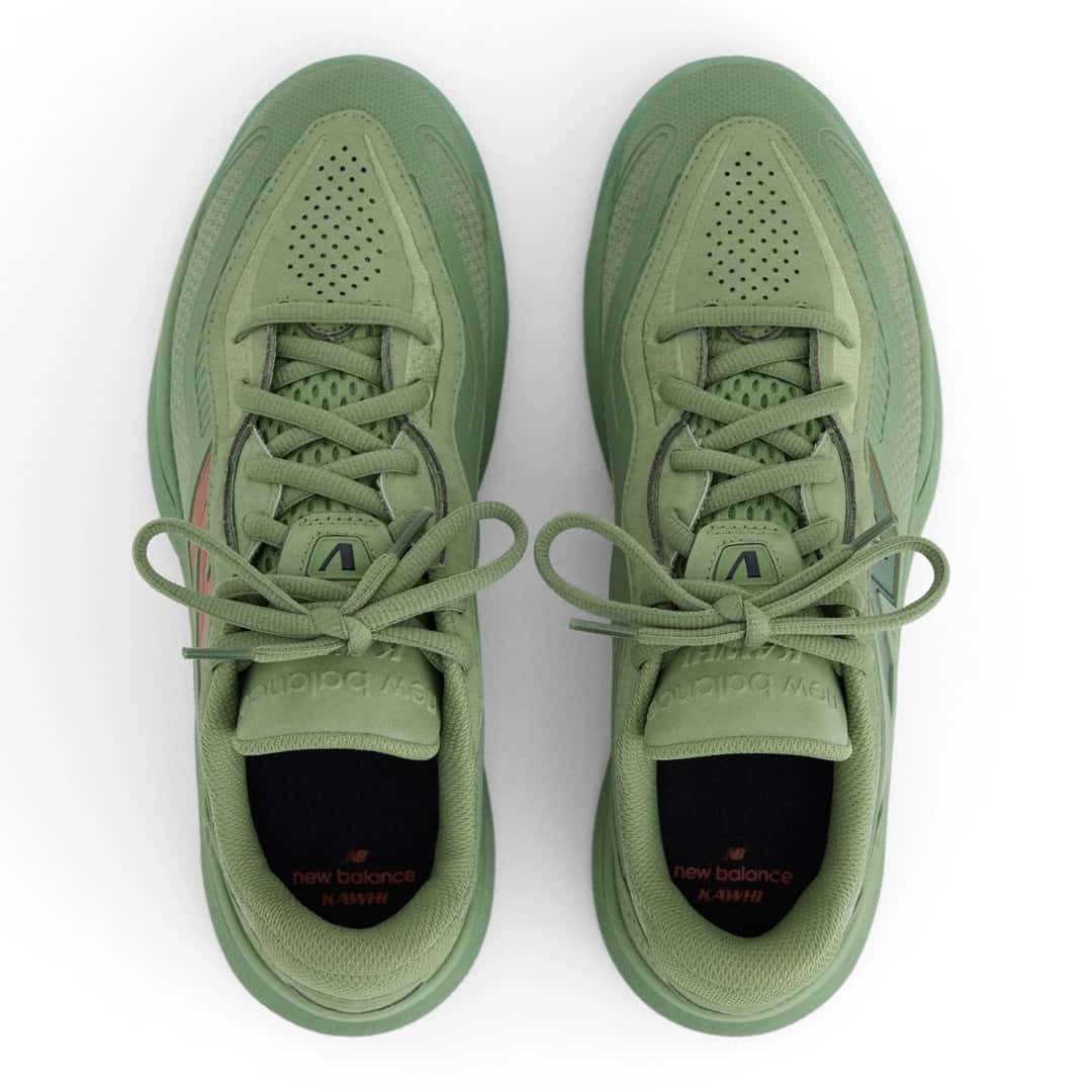 Vista desde arriba del par de New Balance Kawhi 5 Oregano, en verde salvia, con la puntera perforada, la lengüeta con el logo de New Balance, cordones verdes y plantillas negras con las palabras new balance y KAWHI