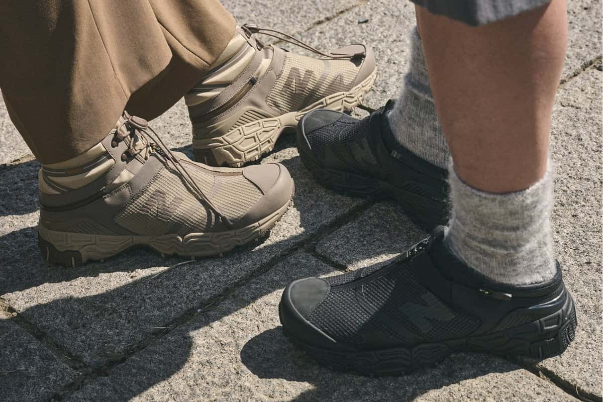 Dos personas con la New Balance Niobium Concept 1 en marrón claro y en negro total sobre una vereda de piedra, con medias grises