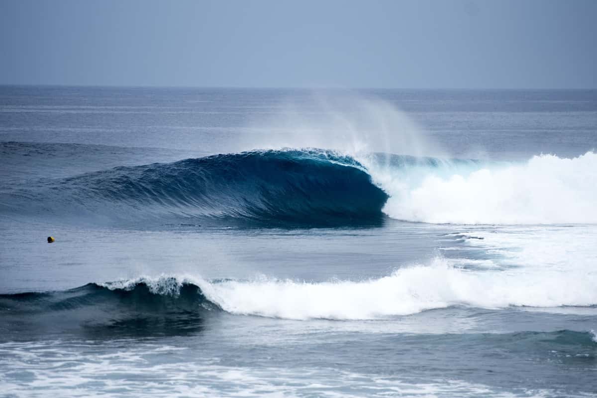 Una ola derecha y tubular rompe sobre el arrecife de Cloud 9, en Siargao, con el mar azul de fondo y espuma blanca en primer plano