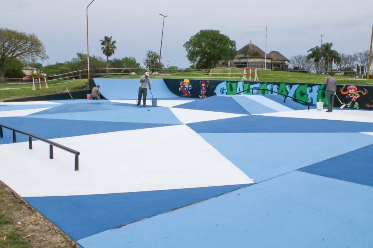 El skatepark de la Costanera Sur de Gualeguaychú con el piso pintado en triángulos azules, celestes y blancos, barandas negras y, al fondo, el mural con el nombre de la ciudad