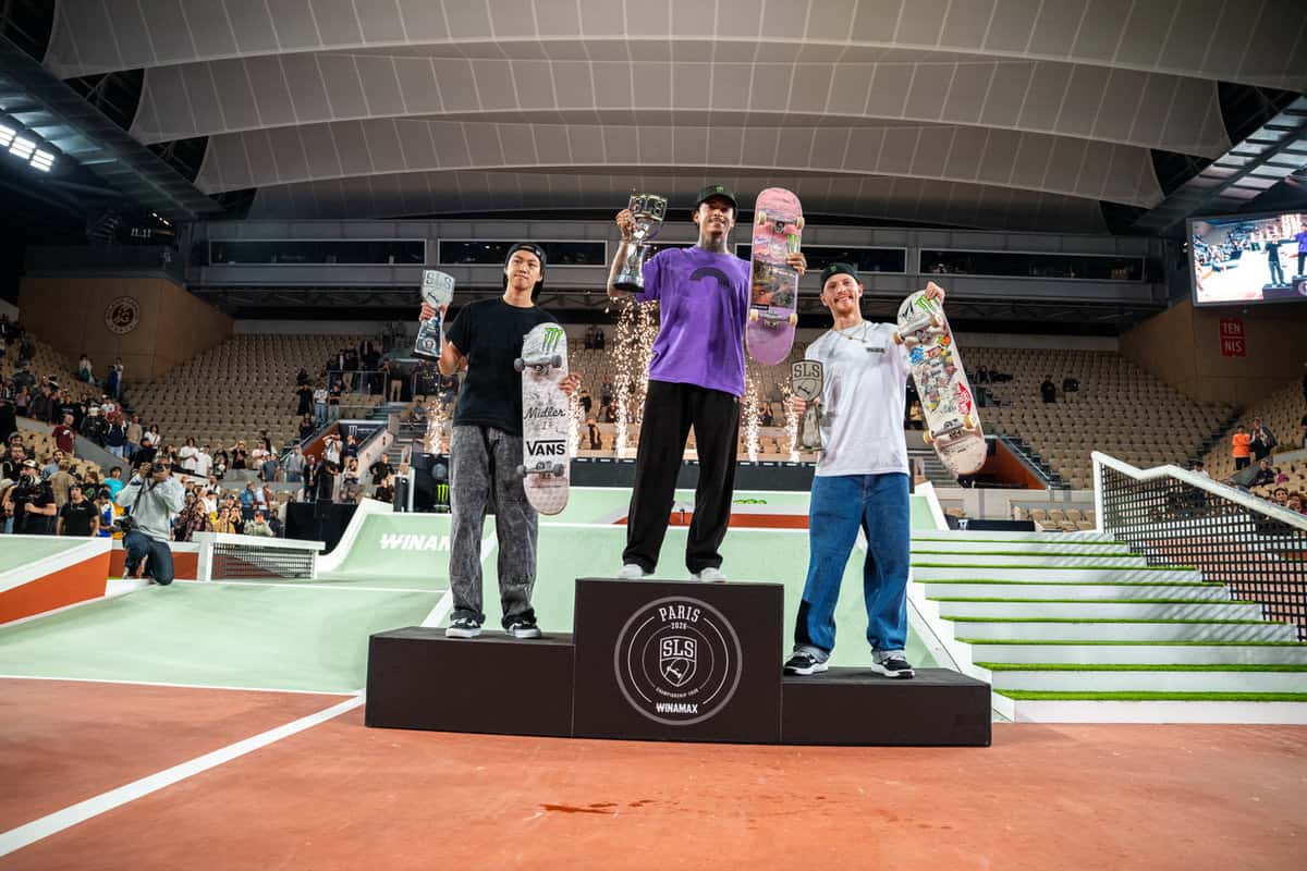 Podio masculino de la Street League en Roland-Garros: Nyjah Huston en el centro levanta el trofeo y su tabla, con Toa Sasaki a la izquierda y Giovanni Vianna a la derecha
