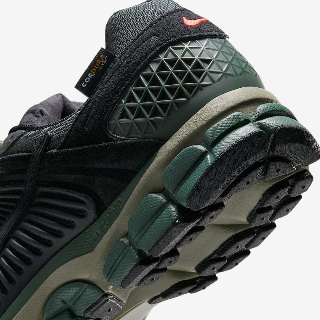 Talón de la Nike Zoom Vomero 5 Cordura Camo Green, con la jaula verde oscuro, el Swoosh naranja y la etiqueta de Cordura