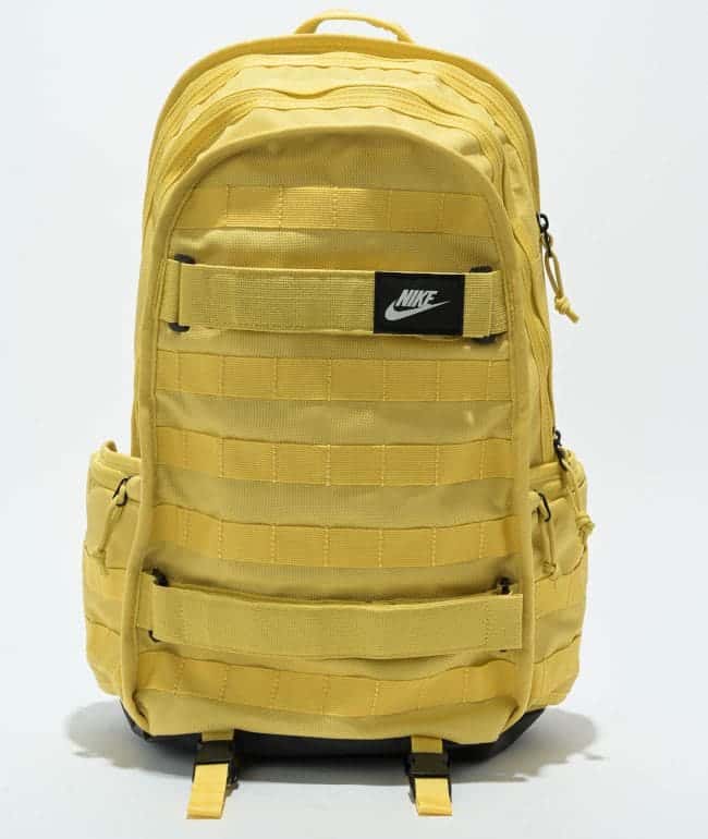Mochila Nike SB RPM amarilla con cintas cosidas al frente, correas para skate y parche negro con logo Nike